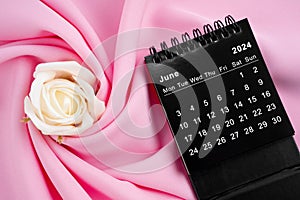 June 2024 desk calendar black color and rose on pink textile