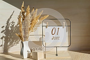 june 1. 1th day of month, calendar date. White vase with dead wood next to the numbers 2022 and stand with an empty photo