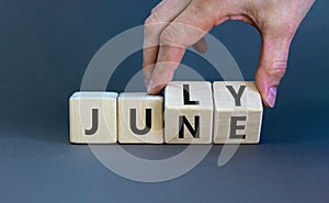 From june to july symbol. Businessman turns wooden cubes and changes the word `june` to `july`. Beautiful grey background, cop