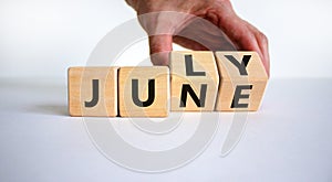 From june to july symbol. Businessman turns wooden cubes and changes the word `june` to `july`. Beautiful white background, co