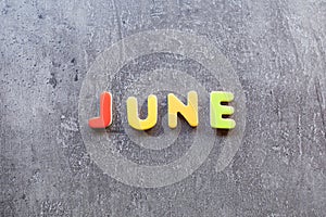 June word written with colorful letters on grey granite stone background