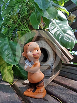 Jungle boy doll and his wooden hut under green leaves
