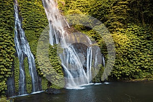 Jungle cascade waterfall in tropical rainforest with rock and crystal pond. Scenic waterfall with fresh water and rainbow in