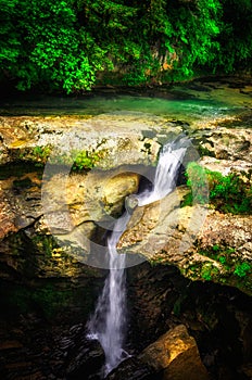 Jungle landscape with flowing turquoise water of georgian cascade waterfall at deep green forest. Mountain of georgia