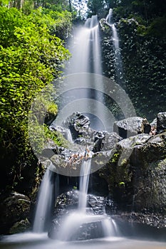 Jungle waterfall cascade in tropical rainforest with rock and turquoise blue pond.