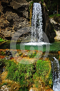 Jungle waterfall cascade in tropical rainforest with rock and turquoise blue pond.