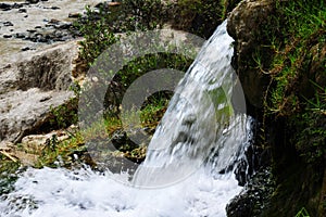 Jungle waterfall cascade in tropical rainforest with rock and turquoise blue pond.