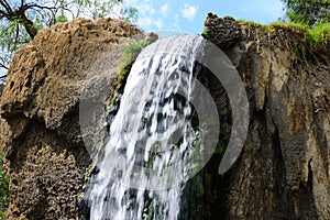 Jungle waterfall cascade in tropical rainforest with rock and turquoise blue pond.