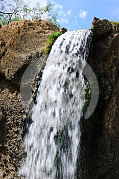 Jungle waterfall cascade in tropical rainforest with rock and turquoise blue pond.