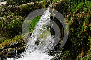 Jungle waterfall cascade in tropical rainforest with rock and turquoise blue pond.