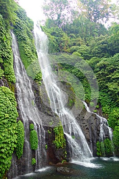 Jungle waterfall cascade in tropical rainforest with rock and turquoise blue pond. Its name Banyumala because its twin waterfall