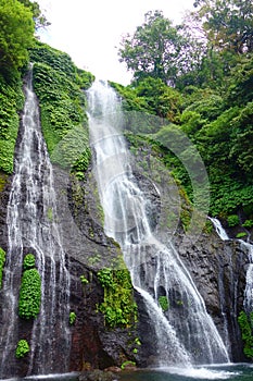 Jungle waterfall cascade in tropical rainforest with rock and turquoise blue pond. Its name Banyumala because its twin waterfall