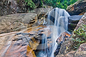 Jungle waterfall with flowing water, large rocks