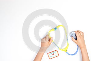 Top view on child`s hands with toy stethoscope on a white background. photo