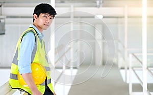 Junior engineer standing in the plant holding helmet and looking outside with copy space