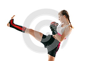 Junior female MMA fighter in sports uniform and gloves training isolated on white background. Concept of sport photo