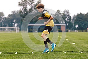 Junior football club player training on soccer ladder. Football training for sport team. Young boy running on agility ladder