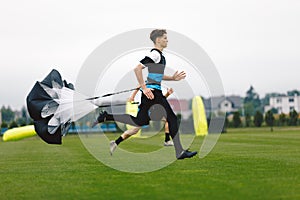 Junior Football Player Running with Parachute. Soccer Endurance and Strength Training