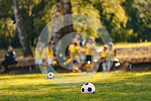 Junior Football Training Pitch. Soccer Balls on Grass Field. School Soccer Team in Yellow Shirts in Blurred Background