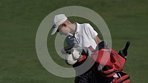 Junior golfer playing golf on summer with hitting shot on green grass