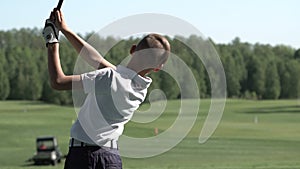 Junior golfer playing golf on summer with hitting shot on green grass