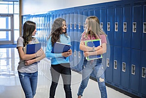 Junior High school Students talking and standing by their locker in a school hallway