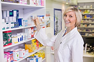 Junior pharmacist taking medicine from shelf