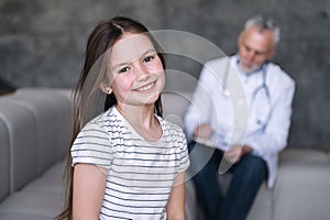 Junior smiling girl patient recovered after illness and doctor on background photo