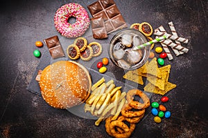 Junk food concept. Unhealthy food background. Fast food and sugar. Burger, sweets, chips, chocolate, donuts, soda, top view