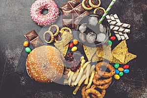 Junk food concept. Unhealthy food background. Fast food and sugar. Burger, sweets, chips, chocolate, donuts, soda, top view