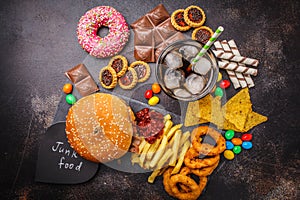 Junk food concept. Unhealthy food background. Fast food and sugar. Burger, sweets, chips, chocolate, donuts, soda, top view