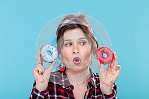 Junk food, diet and unhealthy lifestyle concept - pin-up woman with doughnuts over the blue background