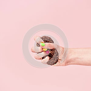 Junk Food. Say no to unhealthy food. Hand squeezing chocolate donut on pink background