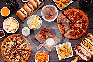 Junk food table scene, overhead view on dark wood