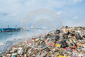 Junk yard near harbor view full of smoke, litter, plastic bottles,rubbish and trash at the Thilafushi local tropical island