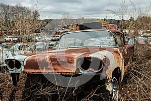 Junkyard rusty old abandoned car in car graveyard