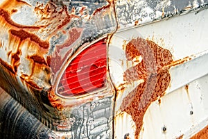 Junkyard Van Red Taillight Surrounded by Rust and Paint