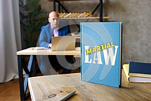 Jurist holds MARTIAL LAW book. Martial law is the temporary imposition of direct military control of normal civil functions or