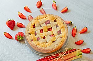 Just baked rhubarb strawberry pie on the gray kitchen background. Veggie berries tart decorated with organic fresh strawberries