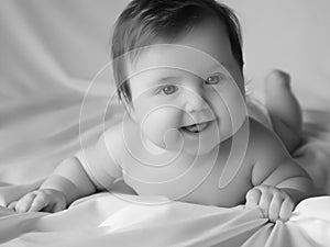 Just beautiful. Cute smiling baby. Cute 3 month old Baby girl infant on a bed on her belly with head up