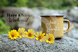 Just breathe. Have a nice weekend. With cup of tea or coffee and yellow tiny flowers decoration on the stone.