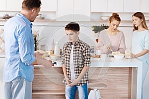 Just caring father punishing his son in the kitchen