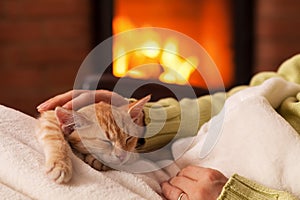 Just chilling by the fireplace - woman hands petting a small tabby cat