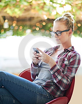 Just chilling and texting. a young woman using her cellphone at home.