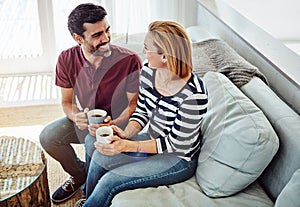 Just a couple on their couch. High angle shot of an affectionate young couple having coffee together at home.