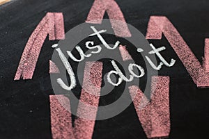 Just do it, handwritten with white chalk on a blackboard.