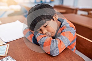 Just five more minutes. a tired elementary school child sleeping on his desk in the classroom.