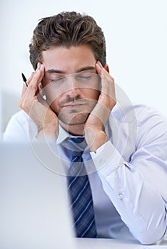 This just gives me one BIG headache. a stressed businessman holding his hands to his head.