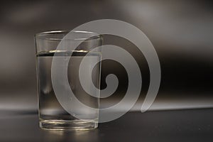 Just a glass of water on a dark wooden table. Mineral water in a glass on a black background. A glass with water