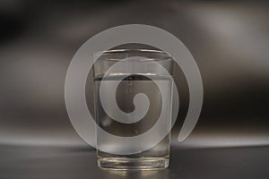 Just a glass of water on a dark wooden table. Mineral water in a glass on a black background. A glass with water